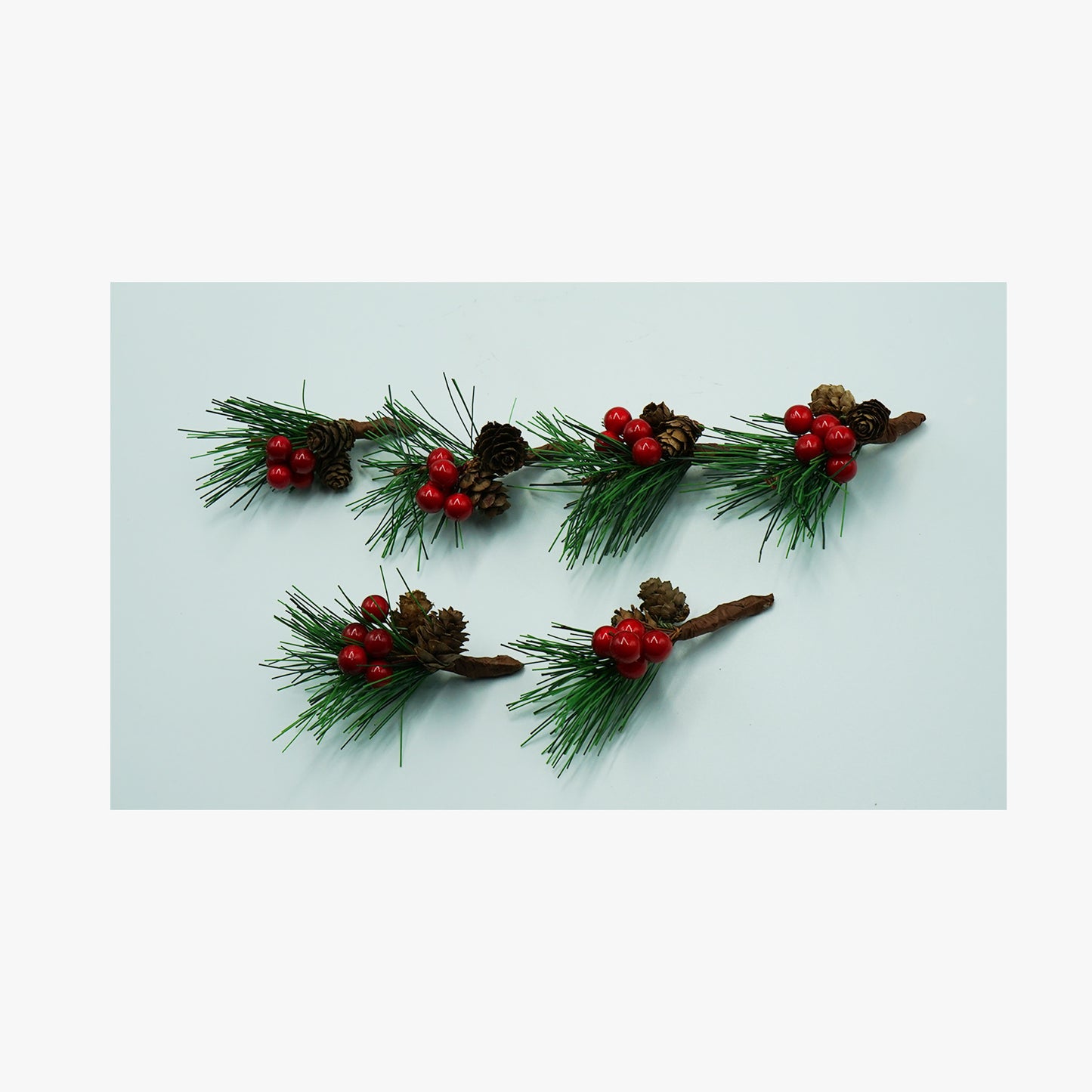 Künstliche Kiefernzweige mit roten Beeren und Zapfen